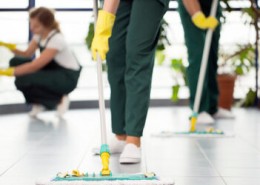 Close-up of person with yellow gloves cleaning the floor by using mop
